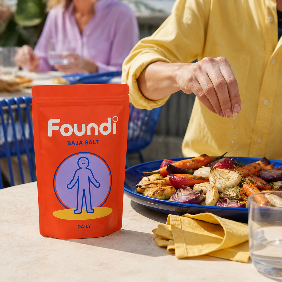 Foundi Daily Baja Salt beside roasted vegetables being seasoned at an outdoor table